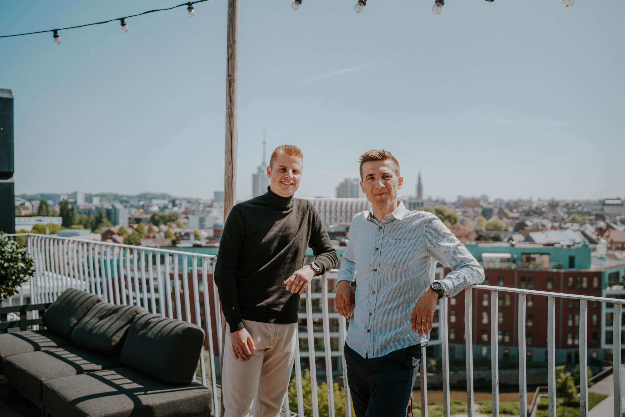 Kristof Borgions et Lars Cappelle sur une terrasse en toiture, avec la ville de Louvain en arrière-plan